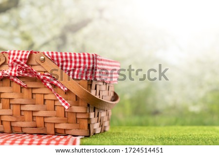 On green grass, a picnic basket against the backdrop of the landscape. A backdrop for relaxing and spending the weekend. Picnic and relaxation Royalty-Free Stock Photo #1724514451