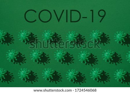 A conceptual pattern on the covid-19 theme. A set of green volumetric models of coronavirus with a hard shadow in rows on a green background.