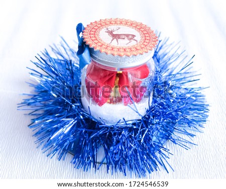 Christmas decoration made of tinsel and cans of snow. inside a red bank and snow. around the jar of blue tinsel. object on a white background