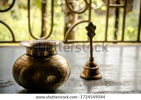 Close up Still Life of antique Holi water pot and bell on rustic floor. Faith, Tradition, Spirituality, Prayer, symbols of peace and Religious Themes. Arts and culture background concept. Copy space  