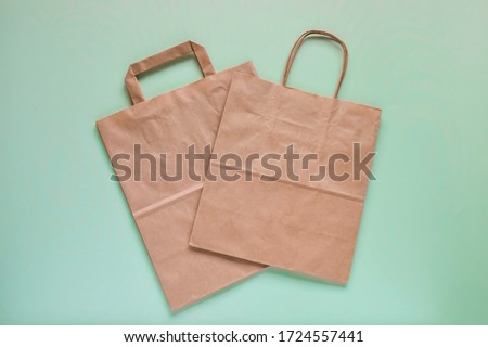 Recycled brown paper shopping bag with handle, isolated on green background, flat lay, mockup. Two folded empty paper bag. Close-up. Selective focus. Copy space. Royalty-Free Stock Photo #1724557441