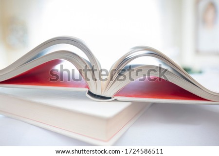 Shallow focus on open book in home environment. Focus on spine of book. Unfocused home environment