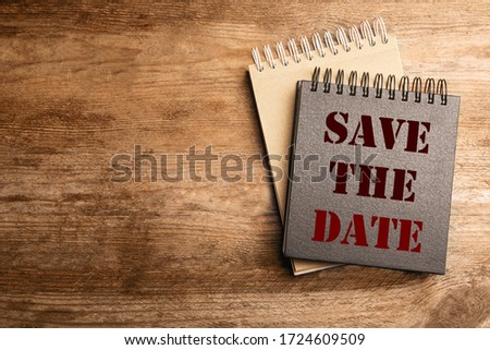 Stylish notebooks with phrase SAVE THE DATE on wooden table, top view. Space for text