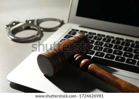Laptop, wooden gavel and handcuffs on grey table, closeup. Cyber crime
