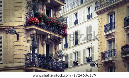 Retro Photo Filter Effect - Beautiful balconies with red and pink flowers, classic building and architecture in Paris, France.