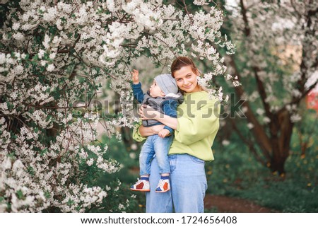 happy mother and son play against the background of a flowering tree. Spring, mother's day.