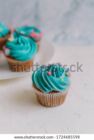 Turquoise cupcake in a white plate on a white background