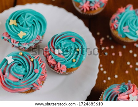 Turquoise cupcakes in a white plate on a wooden background