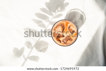 Cup of ice coffee with milk in white bed. Cold brew coffee. Flatlay, top view. Minimalism. Morning with sunlight. Royalty-Free Stock Photo #1724695972