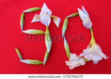 Number 90 written by fresh iris flowers on a red background. Number ninety written in fresh flowers isolated on red. 