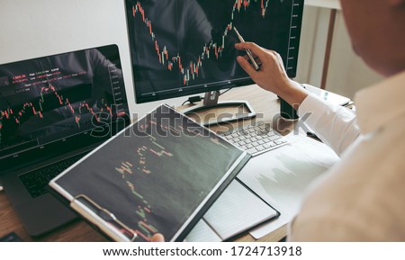 Investor man analyzing the graph of the stock market using a pen pointing to the computer screen. Royalty-Free Stock Photo #1724713918