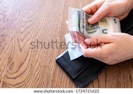 Money and wallet hold in hand. Spending Euro banknotes. Concept image for economy crisis spending review measure to avoid debit unemployed and default. Financial bankrupt stress and fear of recession