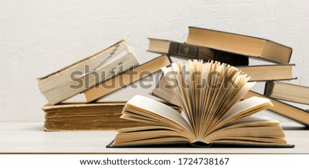 Composition with vintage old hardback books, diary, fanned pages on wooden deck table and abstract background. Books stacking. Back to school. Copy Space. Education background.