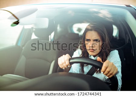 Road rage! Enraged young woman driver shouts and points accusingly.  Profile of an angry young driver. Negative human emotions face expression. Angry woman driving a car Royalty-Free Stock Photo #1724744341