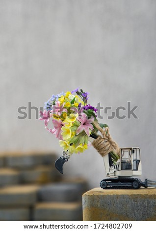 bouquet on the arrow of an excavator. toy exa bright sunny day. Concept of love, business - congratulation, builder's day holiday
greeting card for the construction business