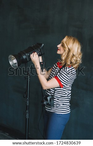 Young beautiful woman photographer works in a photo studio using artificial lighting. Soft selective focus.
