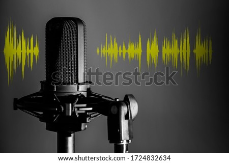 Professional microphone with yellow voice waveform on dark background, sound studio recording 