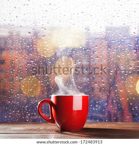 Steaming cup of coffee over a cityscape background
