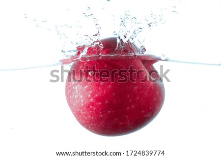 Fresh red apples fall into deep water with large transparent, bubbles splitting, isolated on a white background.