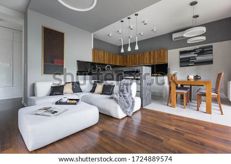 Elegant apartment with kitchen with dining area open to living room with big white corner sofa Royalty-Free Stock Photo #1724889574