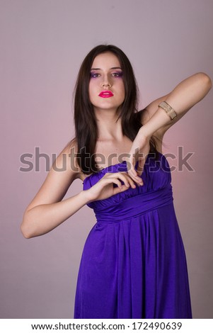 Emotional studio portrait of a beautiful brunette girl in a cocktail dress and lilac bright evening makeup with pink lips