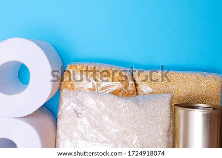 Food supplies crisis food stock for quarantine isolation period on blue background. Peas, rice, millet, canned food and toilet paper. Food delivery, Donation, coronavirus quarantine. Copyspace.