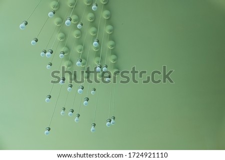 A group of modern green ceiling lights hanging on the green ceiling. Inside the house, the green house is decorated with a chandelier.