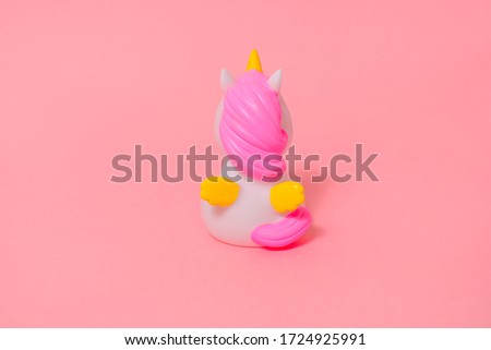 Figurine of a white unicorn with a pink mane and yellow wings on bright pink. Unicorn back. Pop Art. The concept of loneliness.