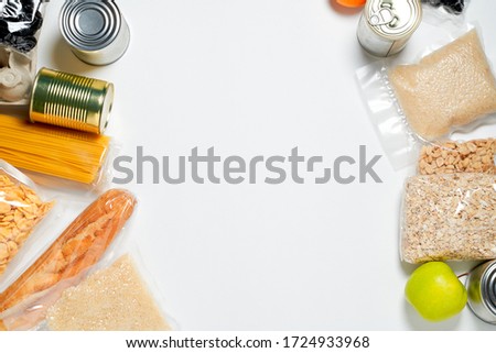 Various foods sealed in plastic bags, cans and fruits on white background, top view.