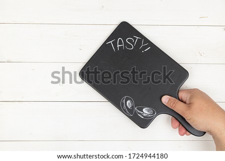 Black food tray in the hand with copy space and white wooden background.