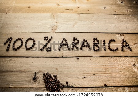 written with coffee beans "100% arabica" on wooden table