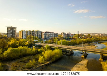 Aerial view of Ivano-Frankivsk city, Ukraine with Bystrytsia river and tall residential buildings under construction in distance.