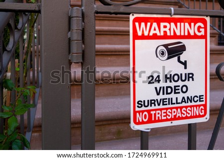 red white and black safety security sign with camera icon and test that read "warning 24hour video surveillance no trespassing 