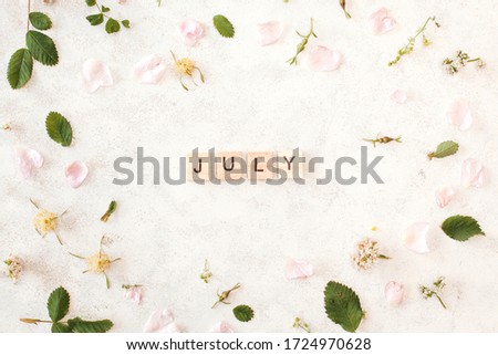 Month of july - white background with rose petals and leaves. Spring floral background.
