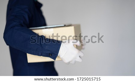 Delivery man employee wearing face mask gloves hold empty cardboard box isolated on white background studio Service quarantine pandemic coronavirus virus 2019-ncov concept
