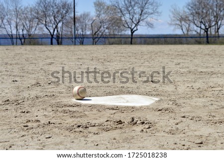 A baseball sits on home plate - with no people around to play the sport.  Parks have been closed to public gatherings and both professional and amateur sports alike.