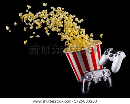 Flying popcorn and video game joystick gamepad isolated on a black background