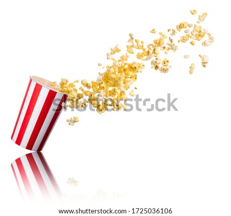 Flying popcorn from paper striped bucket isolated on white background with clipping path. Concept of cinema or watching TV.