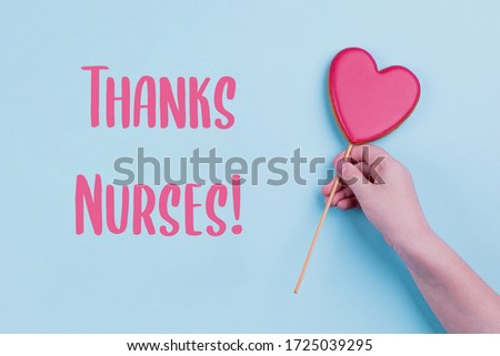 Thanks Nurses Card. Hand holding pink heart.. Holiday, greeting card concept. Blue pastel background. Top view, flat lay
