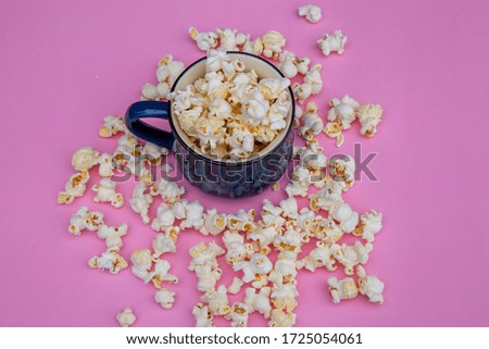 cup with popcorn on purple color background