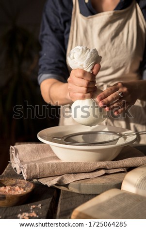 Preparation of cottage cheese - woman straining the milk through a cheesecloth Royalty-Free Stock Photo #1725064285