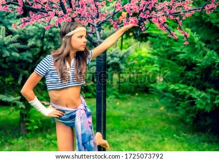 beautiful brunette girl in short striped blue and white shirt, swimsuit and pore on the street in the Park. Fashionable summer glamor concept. Summer walk. Copy space