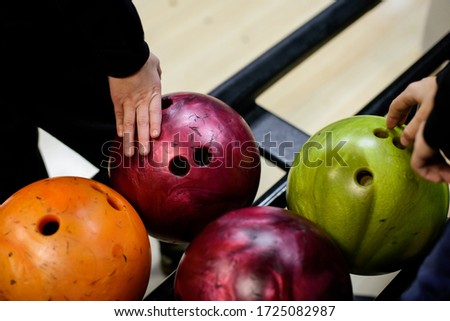 Children's hands taking ball from bowling balls machine