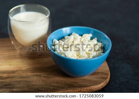 
fresh cheese in a blue bowl, yogurt in a glass and a glass of milk
