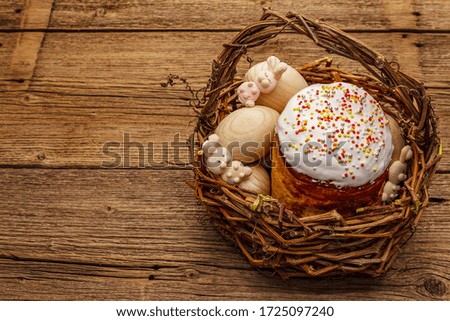 Easter cake, rabbits and eggs in wicker basket. Traditional Orthodox festive bread, vintage wooden boards background