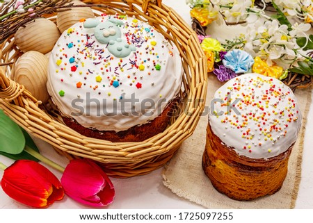 Easter cakes on white putty background. Traditional Orthodox festive bread, wicker basket and wreath, flowers