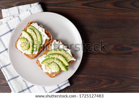 Variation of healthy toasts with avocado cream cheese and whole wheat rye bread on a plate. Delicious snacks and avocado sandwiches. Food composition, tasty Italian meal. Top view, copy space. Royalty-Free Stock Photo #1725127483