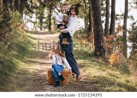Young mother with daughter and son walking for picnic in the forest