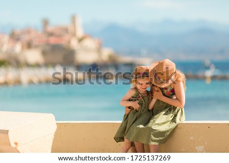 Two sisters walk along the promenade of the ancient city of Antibes (France).