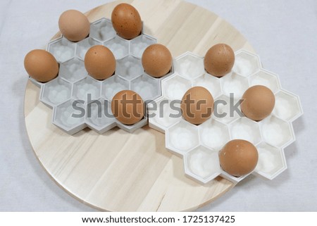 several eggs on white and grey container on round wooden tray with white background